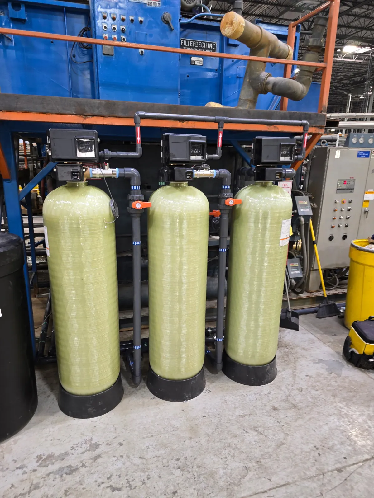 Three progressive water treatment vessels and control valves installed beside an industrial boiler