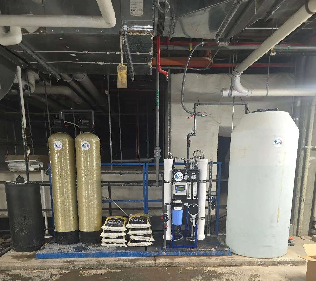 Commercial reverse osmosis treatment train with two pretreatment vessels, an RO skid, salt storage, and a product-water tank